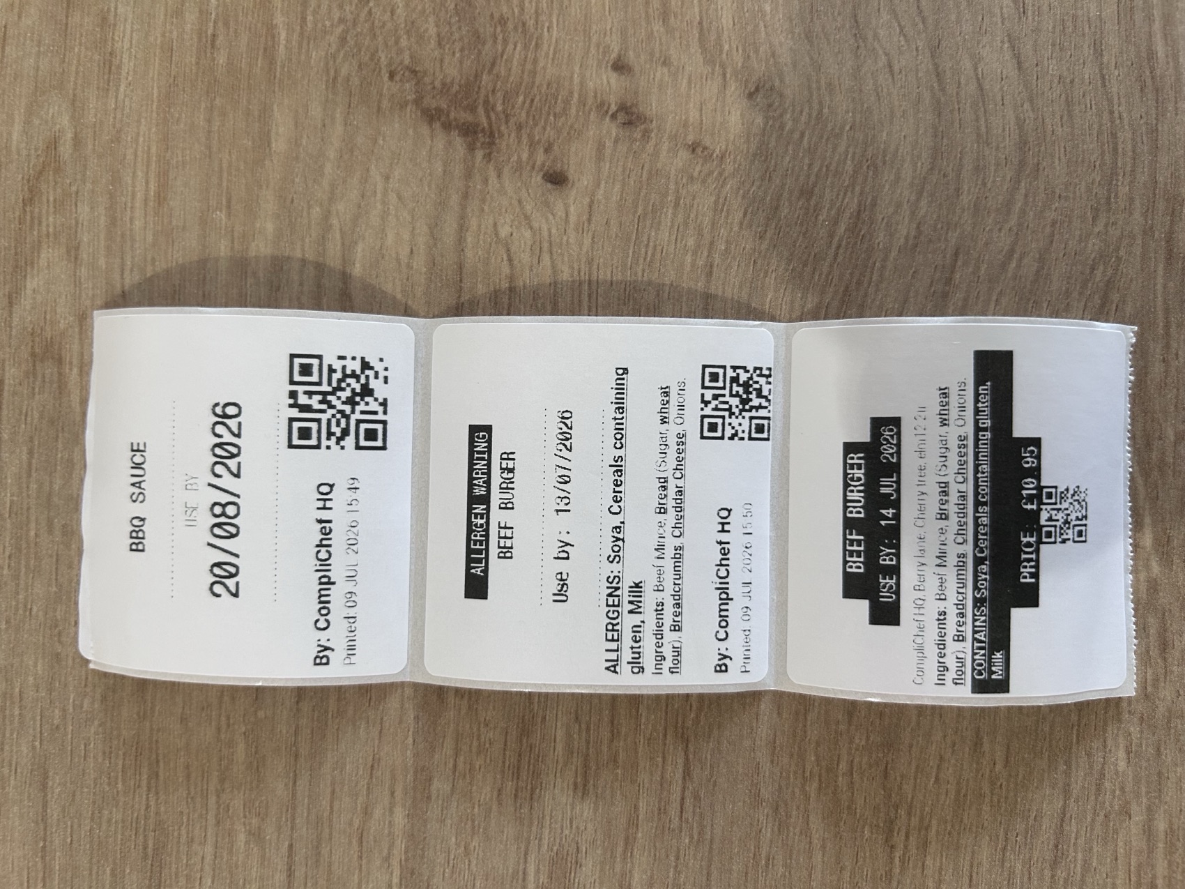 Real printed CompliChef labels — a use-by label, an allergen warning label and a Natasha's Law PPDS sale label