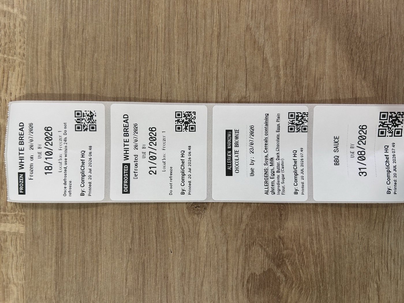 Printed CompliChef labels — frozen white bread, defrosted white bread, chocolate brownie allergen warning and BBQ sauce use-by label